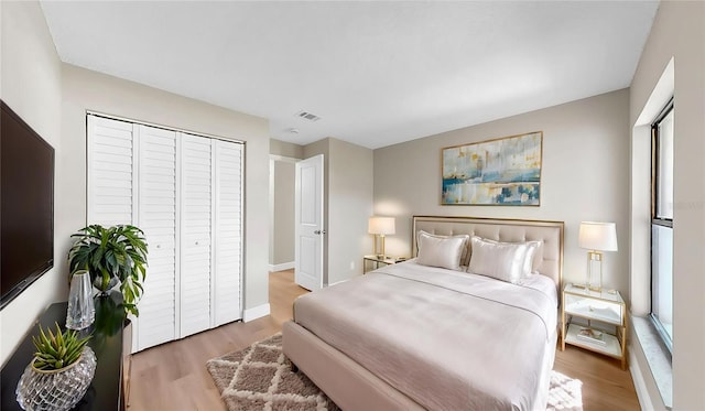 bedroom featuring baseboards, a closet, wood finished floors, and visible vents