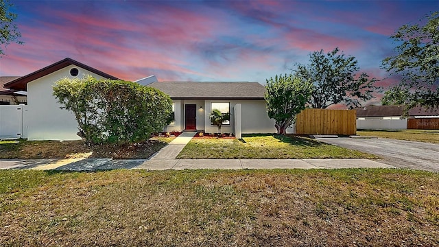 view of front of home featuring stucco siding, a front lawn, and fence