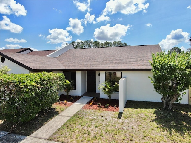 view of front of house featuring a shingled roof, stucco siding, and a front yard