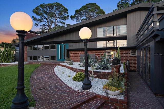 back of property featuring brick siding, a lawn, and a patio