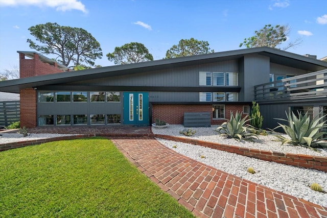 view of front of house featuring french doors, brick siding, a chimney, and a front lawn