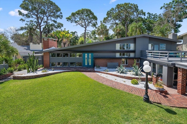 rear view of property featuring a yard and brick siding