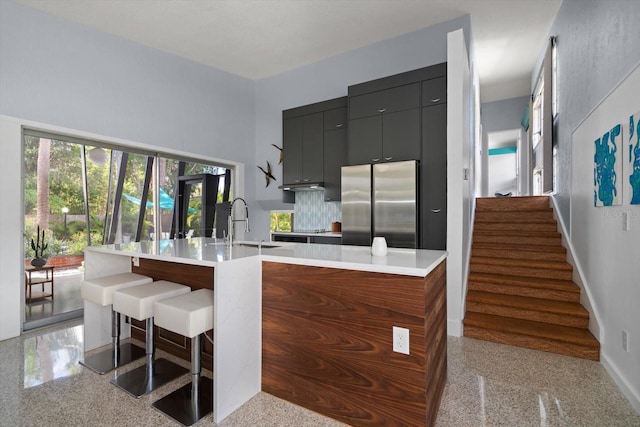 kitchen featuring modern cabinets, a sink, light countertops, baseboards, and freestanding refrigerator