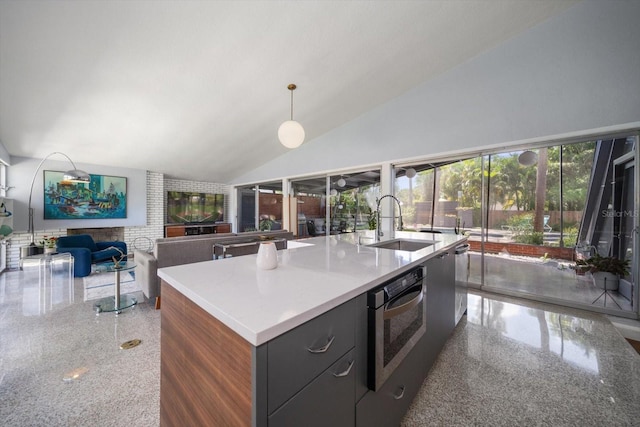 kitchen with a sink, a kitchen island with sink, speckled floor, wall oven, and vaulted ceiling