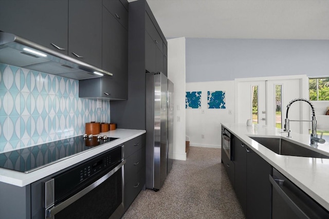 kitchen featuring exhaust hood, appliances with stainless steel finishes, a sink, baseboards, and dark cabinetry