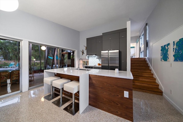 kitchen with freestanding refrigerator, modern cabinets, light countertops, a sink, and a wealth of natural light