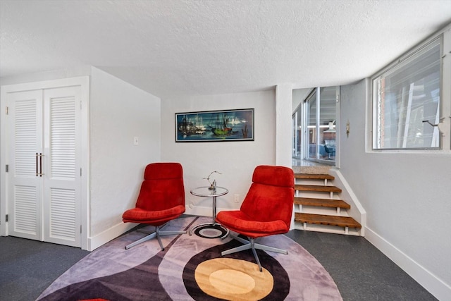 living area with a textured ceiling, baseboards, and stairway