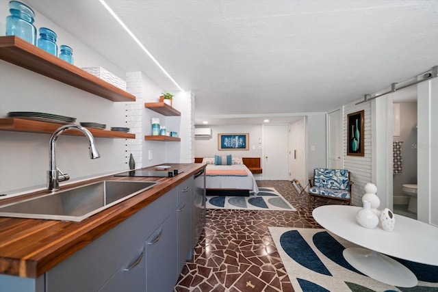 kitchen featuring a wall mounted AC, open shelves, a sink, gray cabinetry, and wood counters
