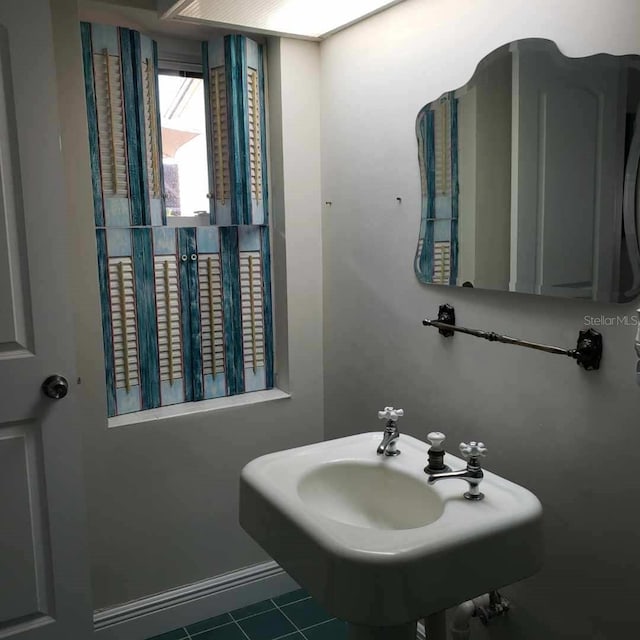 bathroom featuring baseboards, tile patterned flooring, and a sink