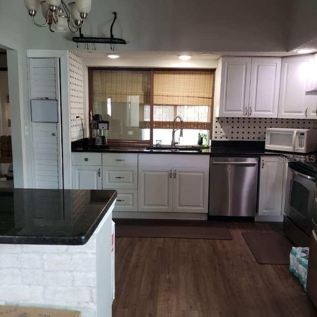 kitchen with a sink, white microwave, dishwasher, white cabinets, and dark countertops