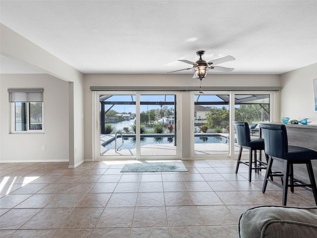6604 Dolphin Cove Dr, Apollo Beach, FL 33572 - living area featuring a ceiling fan, light tile patterned flooring, a water view, and baseboards