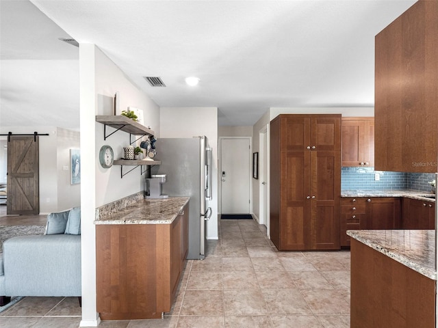 6604 Dolphin Cove Dr, Apollo Beach, FL 33572 - kitchen with open shelves, a barn door, light stone counters, and freestanding refrigerator