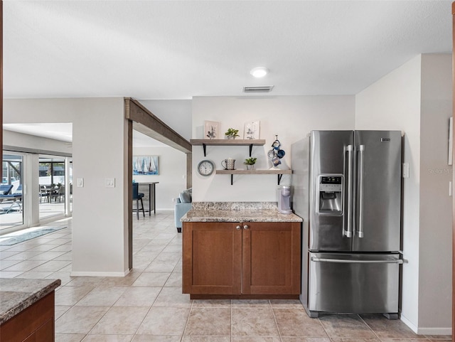 6604 Dolphin Cove Dr, Apollo Beach, FL 33572 - kitchen with stainless steel fridge, open shelves, baseboards, light tile patterned floors, and light stone countertops