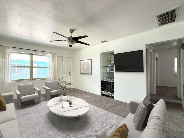 living room with carpet floors, a ceiling fan, a textured ceiling, and visible vents