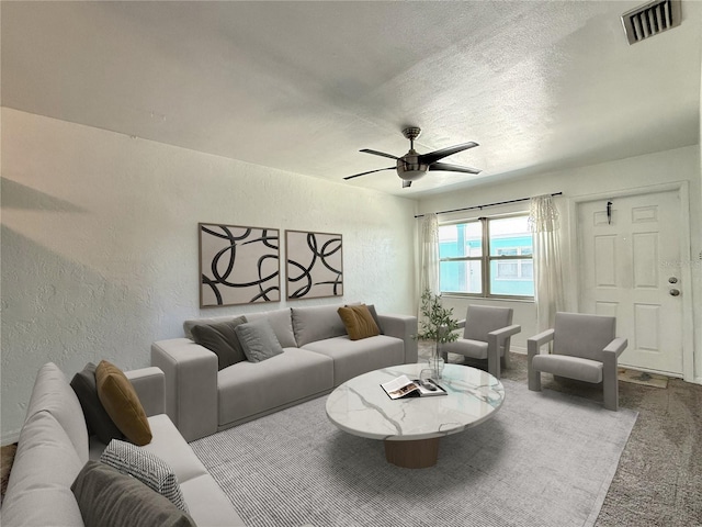 living area featuring carpet floors, a ceiling fan, a textured wall, and visible vents