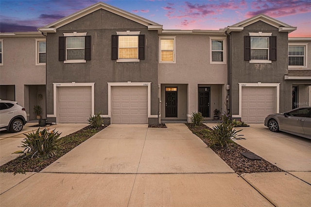 view of property with driveway, stucco siding, and a garage
