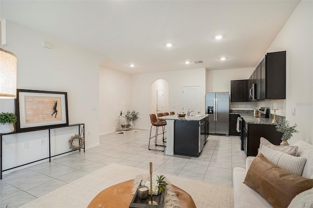 living area with arched walkways, light tile patterned floors, recessed lighting, and baseboards
