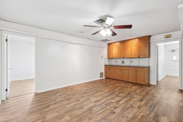 6365 32nd Ave N, Saint Petersburg, FL 33710 - kitchen with a ceiling fan, light wood-style floors, dark countertops, brown cabinets, and baseboards