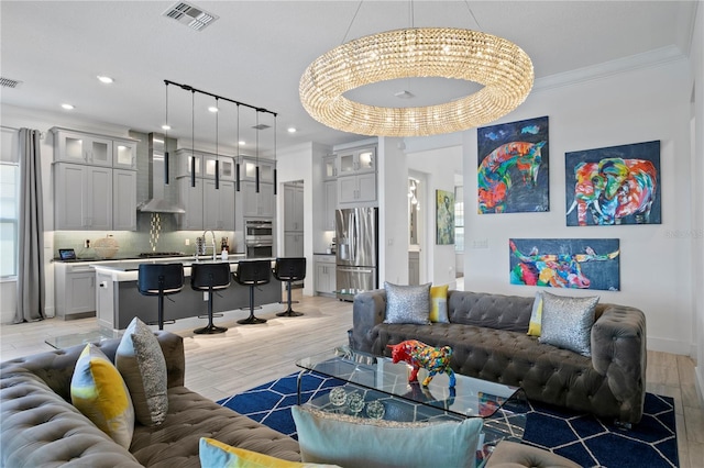 living room with visible vents, ornamental molding, light wood-style flooring, and recessed lighting
