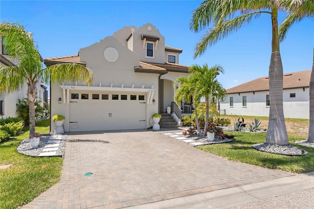 mediterranean / spanish house featuring decorative driveway, a garage, a tile roof, and stucco siding