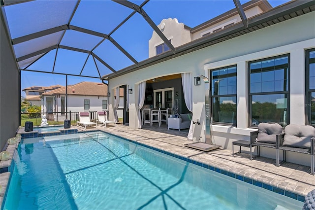 view of pool with a patio, a pool with connected hot tub, a ceiling fan, and a lanai