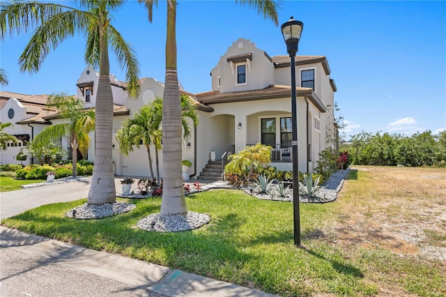 mediterranean / spanish house featuring driveway, stucco siding, covered porch, and a front yard