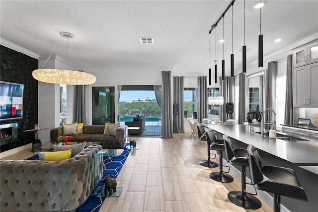kitchen with visible vents, a sink, open floor plan, and glass insert cabinets