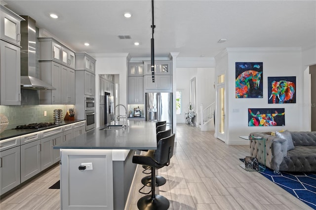 kitchen with stainless steel appliances, gray cabinetry, ornamental molding, and wall chimney exhaust hood