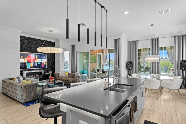kitchen featuring a notable chandelier, a sink, plenty of natural light, visible vents, and ornamental molding