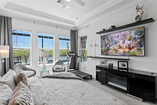living room with carpet flooring, a ceiling fan, a tray ceiling, visible vents, and ornamental molding