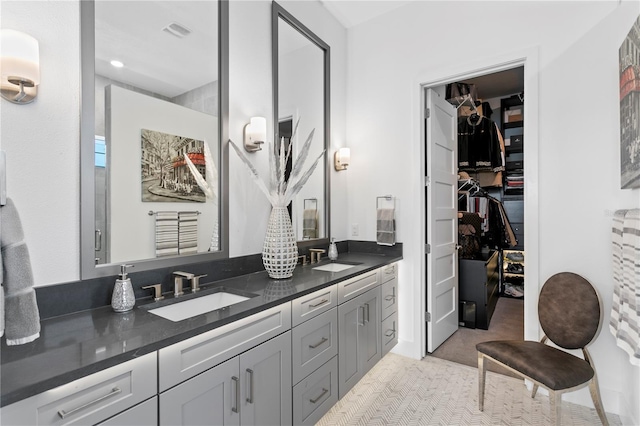 full bathroom featuring double vanity, a sink, a walk in closet, and visible vents