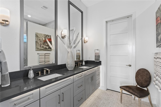 bathroom with double vanity, visible vents, and a sink