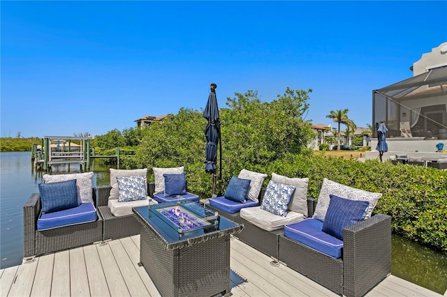 wooden terrace featuring a water view and an outdoor living space with a fire pit