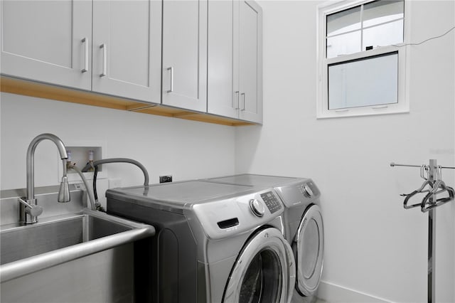 clothes washing area featuring a sink, cabinet space, and washing machine and clothes dryer