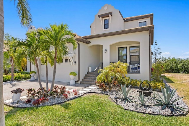 mediterranean / spanish-style home with covered porch, a garage, driveway, and stucco siding