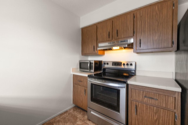 200 Country Club Dr Unit 906, Largo, FL 33771 - kitchen featuring under cabinet range hood, stainless steel appliances, brown cabinets, and light countertops