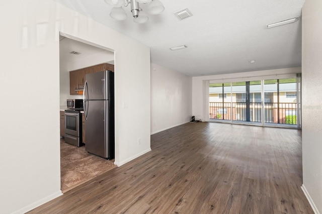 200 Country Club Dr Unit 906, Largo, FL 33771 - unfurnished living room with visible vents, baseboards, wood finished floors, and an inviting chandelier