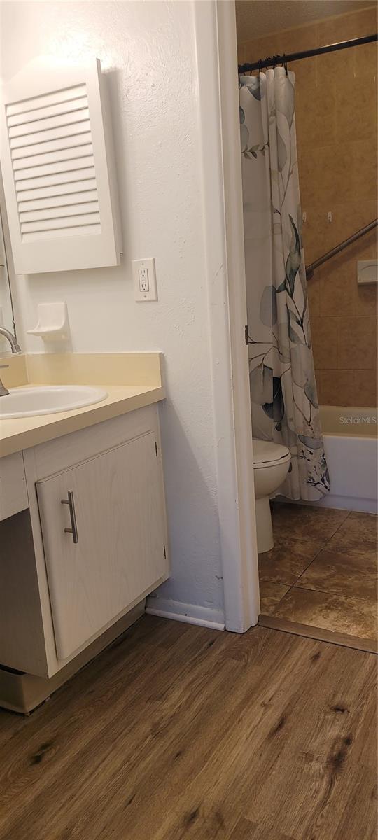 200 Country Club Dr Unit 906, Largo, FL 33771 - bathroom featuring toilet, shower / bathtub combination with curtain, wood finished floors, and vanity