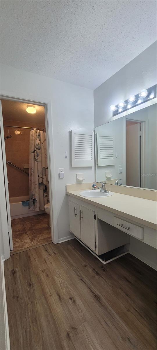 200 Country Club Dr Unit 906, Largo, FL 33771 - bathroom with vanity, shower / bath combo with shower curtain, wood finished floors, toilet, and a textured ceiling