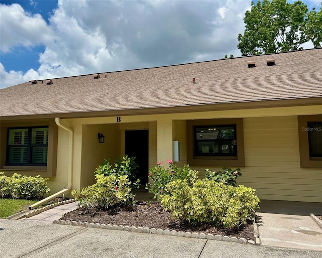view of front facade with roof with shingles and stucco siding