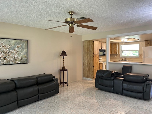 living room featuring ceiling fan and a textured ceiling