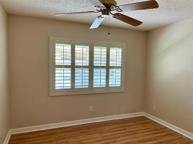 spare room with healthy amount of natural light, wood finished floors, ceiling fan, and a textured ceiling