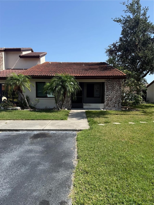 7360 Ulmerton Rd Unit 20F, Largo, FL 33771 - view of front facade with a tiled roof, a front yard, and stucco siding