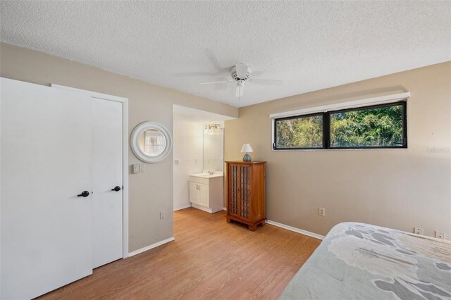 6514 Sunhigh Dr, New Port Richey, FL 34655 - bedroom with light wood-style flooring, a textured ceiling, baseboards, ceiling fan, and ensuite bath