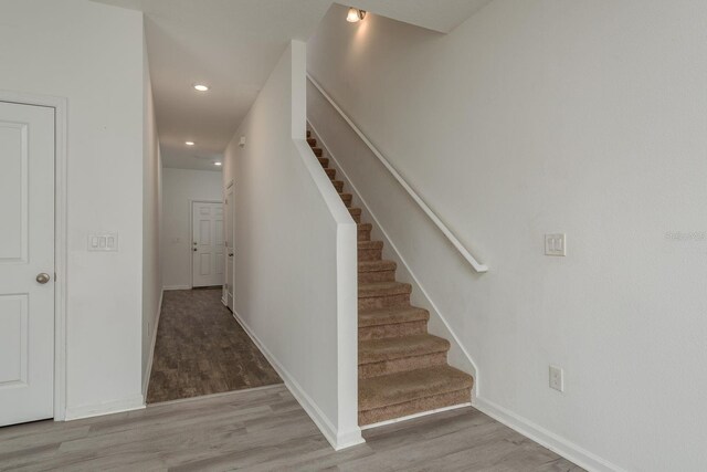 stairs with wood finished floors, baseboards, and recessed lighting