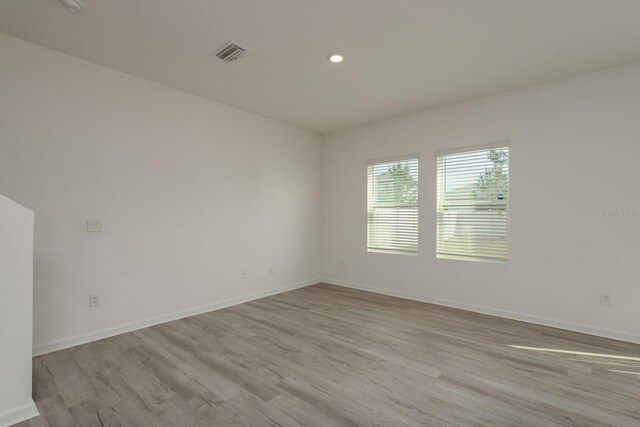 spare room featuring wood finished floors, baseboards, and recessed lighting