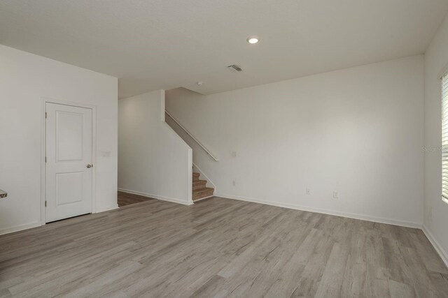 unfurnished living room with stairway, light wood-style floors, baseboards, recessed lighting, and plenty of natural light