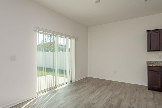 empty room with light wood-type flooring, healthy amount of natural light, and baseboards