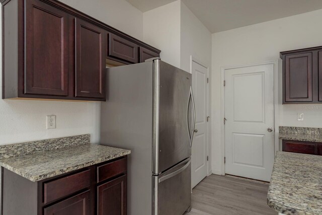kitchen with freestanding refrigerator, light wood-style floors, light countertops, and dark brown cabinets