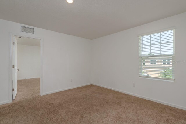 empty room featuring light carpet and baseboards